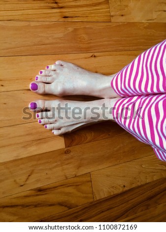 Resting bare feet with Pink toenails on a wood floor
