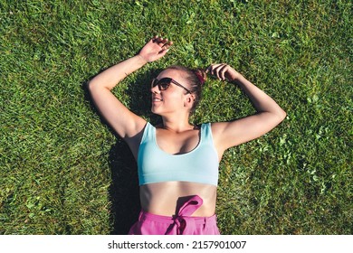 Resting In Grass In Green Garden, Above Top View. Woman Lying Down Relaxing In The Nature. Lazy Girl Day Dreaming Outside In The Park. Happy Calm Healthy Optimism And Peaceful Carefree Daydream.