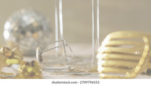 Resting silver muselet and two flute stems on tabletop, scattering gold foil, ribbon, star confetti. Champagne, macro, bokeh, stilllife, closeup, cork, wire