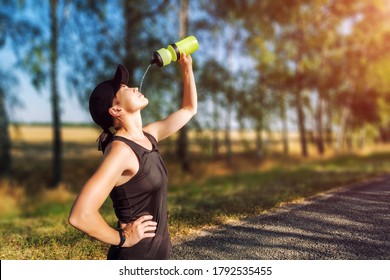 Resting Young Woman Pouring Water From Bottle On Her Face After Hard Workout