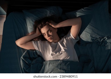 Restless people. Annoyed, Stressed young woman suffering from insomnia, awake in bed at night with headache because of disturbed loud noise, unable sleep. Top view - Powered by Shutterstock