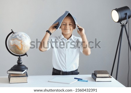 A restless schoolboy boy does not want to study and plays around in class. Concept of bad behavior at school.