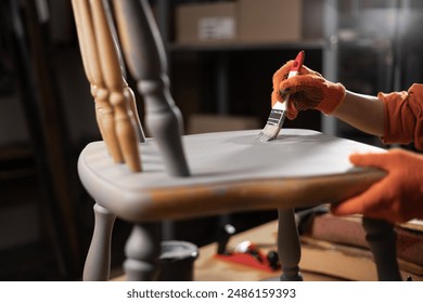 Restorator girl painting old wooden chair in grey color in her workshop. Restoration of old chair. Painting furniture. Furniture renovation and restoration concept. Close-up - Powered by Shutterstock