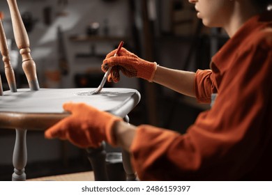 Restorator girl painting old wooden chair in grey color in her workshop. Restoration of old chair. Painting furniture. Furniture renovation and restoration concept. - Powered by Shutterstock