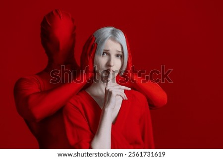 To restrain yourself, a concept. Something within me and something outside of me, makes me feel silent, externally and internally condemned. Mysterious red hands gag a woman in a red dress against a