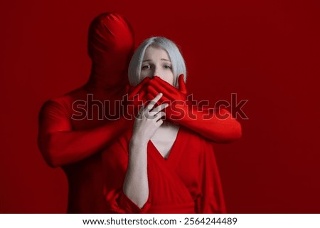 To restrain yourself, a concept. Something within me and something outside of me, makes me feel silent, externally and internally condemned. Mysterious red hands gag a woman in a red dress against a