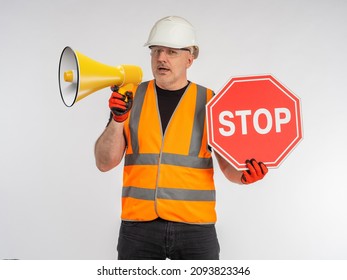 Restriction Due To Renovation Work. Stop Sign In Man Hand. Builder Or Road Worker With Megaphone. Danger Due To Road Work. Red Prohibiting Sign In Hand Of Builder. Ban Concept.