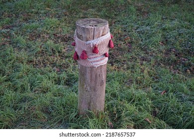 A restrictive roadside pole decorated with knitwear against a background of grass with hoarfrost in December. Berlin, Germany 
