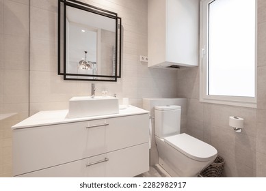 Restroom with glossy white wooden furniture, porcelain sink and black metal framed mirror - Shutterstock ID 2282982917