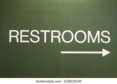 A restroom sign pointing to the right