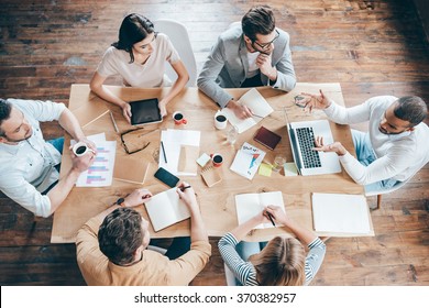 Results And Teamwork. Top View Of Group Of Six People Discussing Something While Sitting At The Office Table