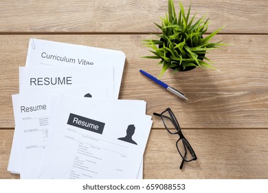 Resume applications on wooden desk ready to be reviewed - Shutterstock ID 659088553