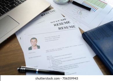 Resume, pen, magnifier, laptop on your desktop. job search - Shutterstock ID 706359943