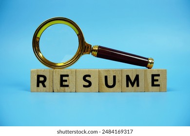 Resume with wooden blocks alphabet letters and Magnifying glass on blue background - Powered by Shutterstock