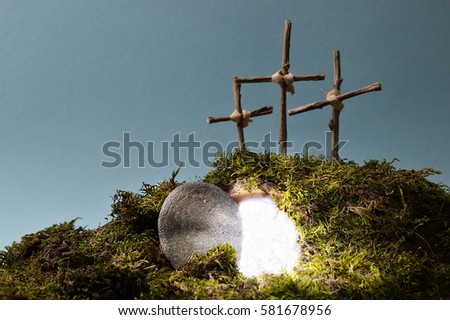 resurrection garden as easter decoration with a stone near the empty tomb filled with blinding light and three crosses on a hill above