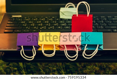 Retail colorful paper shopping bags on notebook keyboard. business concept about e-commerce, online shopping and global network online business that everything can be bought easily by using internet.