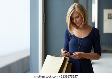 Retail On The Move With Her Mobile Phone. A Young Woman Enjoying Some Retail Therapy While Always Connected With Her Cellphone.