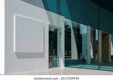 Retail shop store front or commercial office space on ground level of building, with sunlight and shadows on wall. Background for brand logo mockup template..