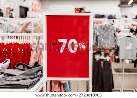 Retail store interior with red 70 percent sale sign and clothing racks. Seasonal discount, fashion sale promotion, shopping concept, consumer marketing and retail business with copy space.