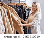 Retail store, woman and choose clothes with smile on sale, promotion and discount in boutique. Mall, female person or customer in San Francisco for shopping, outfit search and quality assurance