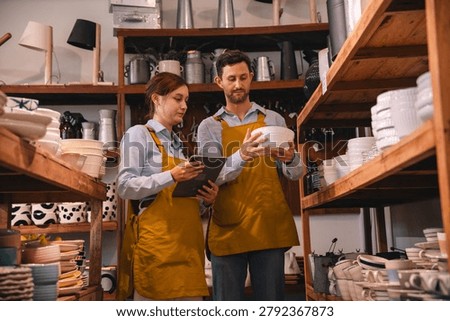 Retail worker inventory checking ceramic bowl in pottery shop