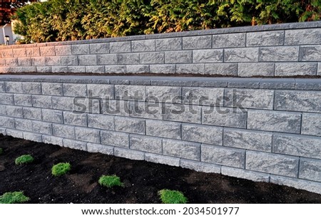 retaining wall closeup gray concrete blocks 2 tier wall existing garden landscape 