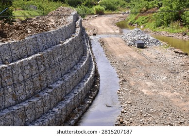 Retaining wall constructed from gabion baskets filled with stones viewed from the side outdoors, Gabion retaining wall