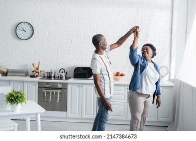 Retired African American Couple Smiling While Dancing In Kitchen