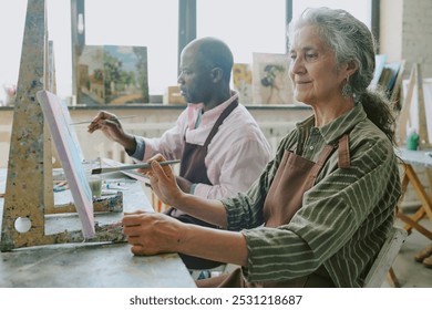 Retired biracial couple painting on canvases together during art therapy in modern studio - Powered by Shutterstock