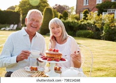 Retired Couple Enjoying Afternoon Tea In Garden At Home