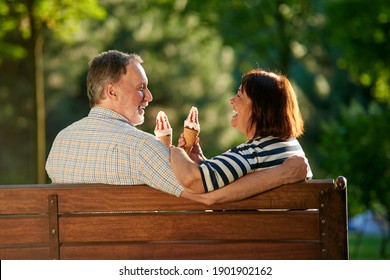 Retired couple on the park bench eating ice-cream. Loving mature man and woman sits outdoors. - Powered by Shutterstock