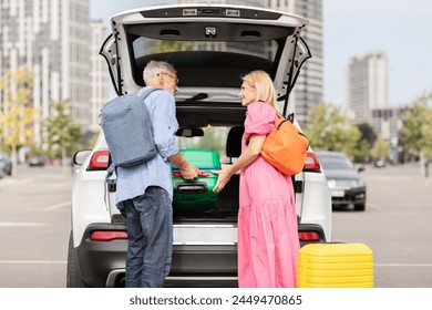 A retired couple puts their luggage into the trunk of their car, symbolizing the freedom and activity of senior life - Powered by Shutterstock