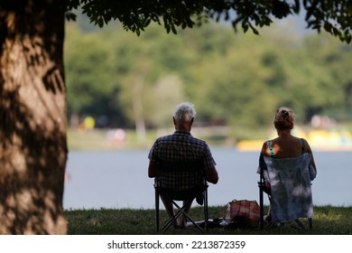 Retired Couple Rest In Front Of A Lake.   France. 