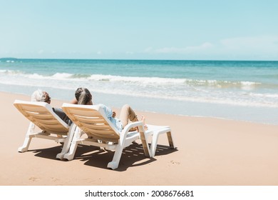 Retired Couple Resting On A Adirondack Chair By The Beach In The Sunlight And Clean Sandy Beach. Retirement Planning Ideas And Happy Life.