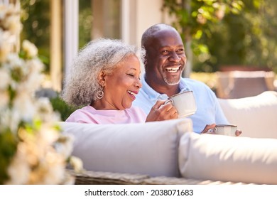 Retired Couple Sitting Outdoors At Home Having Morning Coffee Together - Powered by Shutterstock