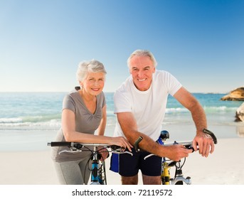 Retired Couple With Their Bikes On The Beach