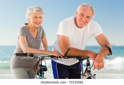 Retired Couple With Their Bikes On The Beach