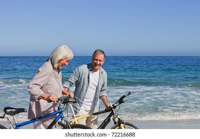 Retired Couple With Their Bikes On The Beach