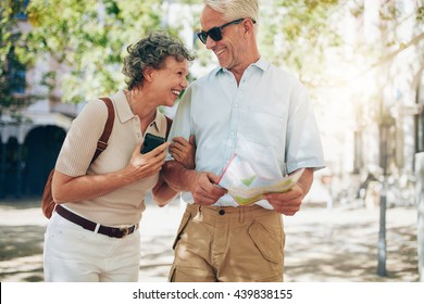 Retired couple walking around the town with a map. Smiling mature man and woman roaming around the city. - Shutterstock ID 439838155
