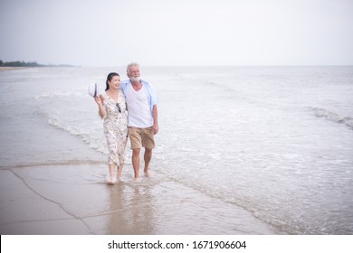 Retired Couple Walking On The Beach.happy Senior Man And Woman  Holding Hands Together With Love And Care In Romantic Mood.Positive Relationship Of Old People Concept