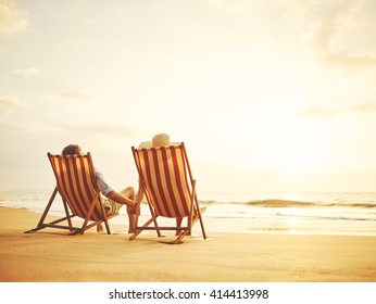 Retired couple watching sunset in vintage beach chairs  