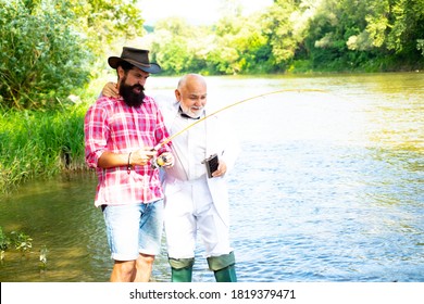 Retired Dad And Mature Bearded Son. Happy Fly Fishing. Portrait Of Two Men On Holiday. Summer Weekend. Man Catching Fish. Trout Bait. Slightly Older. Fun And Relax. Elegant Bearded Man Drinking