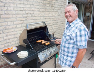 Retired dutch senior man grilling hamburgers in his back yard on a summer day