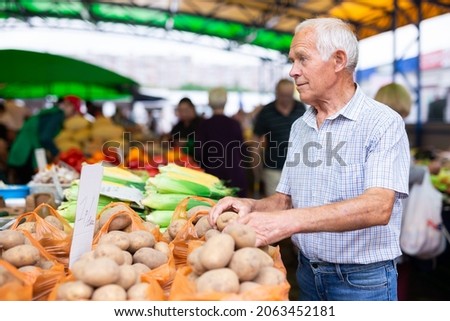 retired european man buys potatoes in market