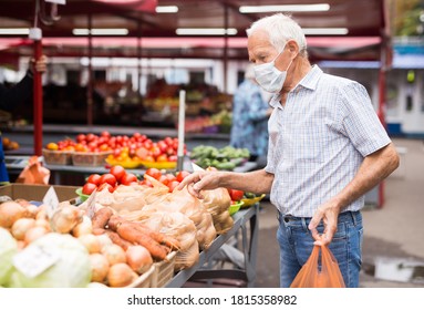 pensionierter europäischer Mann mit medizinischer Maske, der sich vor dem Kauf von Kartoffeln auf dem Markt schützt