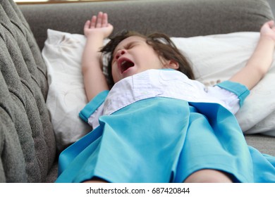 Retired Exhausted Little Girl In Uniform Sleeping On Sofa At Home.Girl Has No Power After School, Take Rest On Couch.Lacking Of Sleep Effect To Child Growing.Selective Focus
