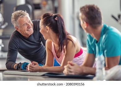 Retired fit man laughs along with younger gym members post workout lying on the mats on the ground. - Powered by Shutterstock