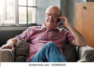 Retired Hispanic Man Talking On Phone Sitting At Living Room. Discuss Important Questions.