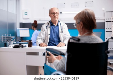 Retired lady in wheelchair provides health updates to senior male physician at hospital. Elderly doctor listens closely as female pensioner patient explains her medical concerns during clinic visit. - Powered by Shutterstock