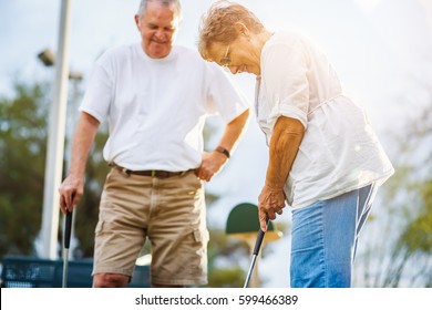 Retired Lifestyle Of Senior Couple Playing Mini Golf